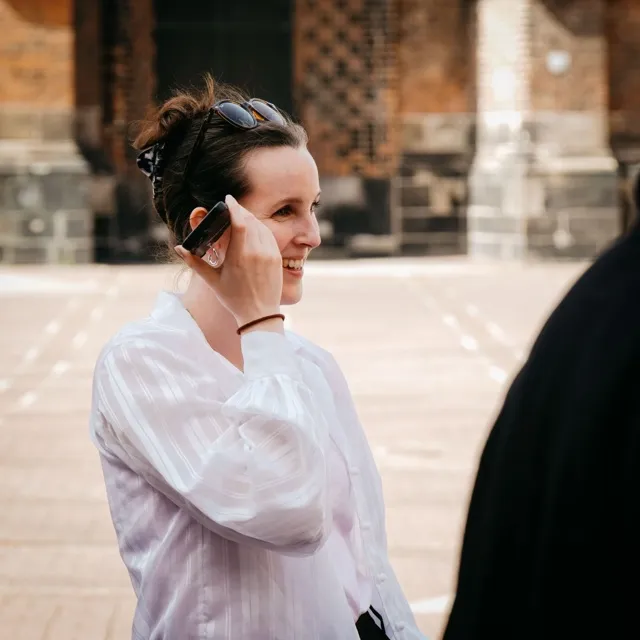Frau hört lächelnd eine Audio-Station auf einer Tour